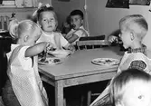 Barn sitter runt ett bord och äter i köket. Holtermanska daghemmet 1953.