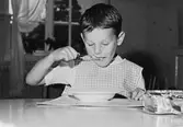 En pojke som äter mat på Holtermanska daghemmet 1953.