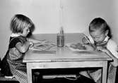 Två barn som sitter och målar vid ett bord. Holtermanska daghemmet 1953.