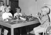Några barn sitter och målar vid ett bord. Holtermanska daghemmet 1953.