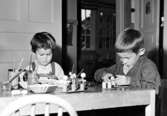 Två barn som leker vid ett bord. Holtermanska daghemmet 1953.