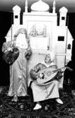Två vuxna personer utklädda i orientaliska kläder, båda hållandes var sitt instrument. I bakgrunden står ett orientaliskt palats i mini-format. Holtermanska daghemmet 1973.