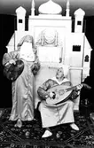 Två vuxna personer utklädda i orientaliska kläder, båda hållandes var sitt instrument. I bakgrunden står ett orientaliskt palats i mini-format. Holtermanska daghemmet 1973.