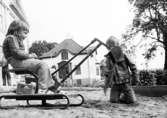 Två barn som leker med en grävskopa i sandlådan. Holtermanska daghemmet juni 1974.