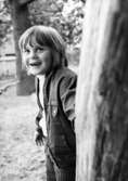 Ett barn som tittar fram bakom en trädstam. Holtermanska daghemmet juni 1974.