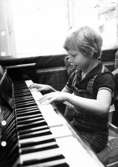 En pojke spelar piano. Holtermanska daghemmet maj 1975.