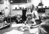 Fem barn som ritar tillsammans med en lärarinna. Holtermanska daghemmet maj 1975.