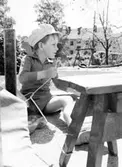 En pojke som sitter utomhus. Holtermanska daghemmet, okänt årtal.