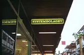 Exteriör av Systembolagets skylt på Brogatan. Mölndalsbro i dag - ett skolpedagogiskt dokumentationsprojekt på Mölndals museum under oktober 1996. 1996_1283-1300 är gjorda av högstadieelever från Åbyskolan 8A, grupp 3. Se även 1996_0913-0940, gruppbilder på klasserna 1996_1382-1405 och bilder från den färdiga utställningen 1996_1358-1381.
