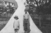 Syskonen Lillemor (givarens mor) och Lasse tältar framför huset på Barnhemsgatan 13, 1930-talets början.