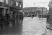 Översvämning i korsningen Kvarnbygatan-Frölundagatan samt Göteborgsvägen-Kungsbackavägen, 1951. I bakgrunden ses biografen Röda Kvarn (Kvarnbygatan 1).