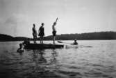 Män och kvinnor på en flotte samt en person i en kajak, troligtvis vid Tulebosjön 1930-tal.