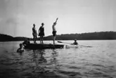 Män och kvinnor på en flotte samt en person i en kajak, troligtvis vid Tulebosjön 1930-tal.
