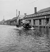 På huset t.h i bild står fabriksförsäljningen, enligt Karl är kortet taget mot spårvagnshallarna vid Mölndalsbro. Kortet är taget i samband med  översvämningen i Mölndal i februari 1943.