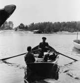 Adolf Österman ror här över till sitt postområde på Södermöja och har
sonen Arne med i båten.
