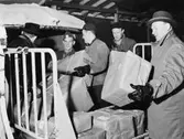 Paket lastas in i möbelbuss från Årsta Bilexpress. Längst till
höger förste kontrollör Gunnar Lagerberg och andre från höger
postassistent Åke Sjögren, båda från postdirektionen i Stockholms
D.,hjälper till med lossning och lastning. Tredje från höger är Rune
Lindqvist, K Gps.