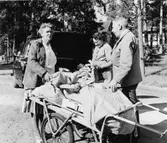 Posten har kommit till Ljusterö med transportören Fritjof Almgren.
Poststationsföreståndare fröken Astrid Karlsson, Ljusterö och
lantbrevbärare Stina Johansson, t.v., möter upp.