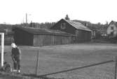 En pojke står vid ett fotbollsmål. I bakgrunden ses en lada och garage tillhörande Hällesåker 4:56. Relaterade objekt: 2002_0992 - 0995.