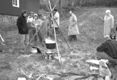 Familjesöndag vid Börjesgården, 1994-05-15. Museichef Mari-Louise Olsson (med vitt hårband) står vid en öppen eld och samtalar med besökare.