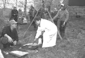 Familjesöndag vid Börjesgården, 1994-05-15. Museitekniker Alf Garthman sitter på huk och grillar. Museichef Mari-Louise Olsson kokar mat över öppen eld.