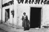 En kvinna står utanför Åkerströms manufakturaffär på Sörgårdsgatan 2 i Krokslätt. Okänt årtal.