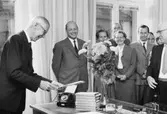 Överdirektör Hultman är glad åt en bokgåva och adress. Närmast
honom står byrådirektör Bertil Lindskog. Längst t.h. byrådirektör
Bertil Åhsberg, som höll hyllningstalet å personalens vägnar.