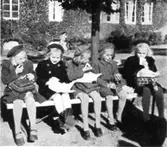 Fem flickor sitter på en bänk och har matrast utanför Kvarnbyskolan (Centralskolan), okänt årtal. Avfotograferad ur 