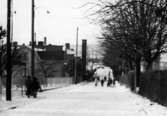 En samling barn promenerar på Brunnsgatan i Ryet, Mölndal, en vinter på 1960-talet.