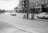 Biltrafik på Göteborgsvägen i Mölndal i riktning mot söder på 1960-talet. I bakgrunden ses närmast huset Göteborgsvägen 1-5. Huset kallas Centrumhuset eller Frändbergska huset.