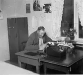 Man sitter och skriver, troligtvis är det
poststationsföreståndaren. Poststationen i Gråträsk inrättades 1914
och ersattes av ett postställe 1975. Poststället drogs in 1976.