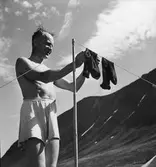 Man hänger strumpor på tork. Fjällandskap i bakgrunden.