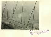Brooklyn Bridge
Exteriör. Detalj. Manhattans byggnader i bakgrunden. Vajrar i dimma i förgrunden.