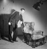 Herrkläder
Man i kostym lutad mot fåtölj