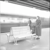 Västra tunnelbanan, tunnelbanebänk med kvinna, barn och man. Tunnelbana som åker förbi.