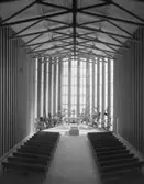 Krematorium i Lund, modell
Interiör. Mittgång mellan bänkrader, i fonden kor med ljus från höga fönster