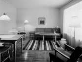 Hushållsseminarium
Interiör, sällskapsrum med matsalsbord samt sittgrupp vid randig matta i fonden