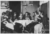 Gestad, södra syförening. En samling kvinnor sitter runt ett bord och syr.