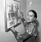 Konstnär Caje Huss justerar en av sina målningar vid hängning av en utställning