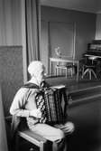 Mölndals-Korpen anordnade aktiviteter för äldre i Mölndal året 1984. En okänd man spelar gammeldans på dragspel i Kållereds kommunalhus på Streteredsvägen 3. Huset revs i början av 1990-talet.