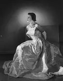 Modell i paisley-mönstrad aftonklänning, vita handskar och halsband. Höst.