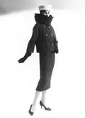 Mannekängen Erika Sundt i tweeddräkt med hög krage, skorstenskrage, handskar, pumps och vit pälshatt. Original från Hubert de Givenchy, NK:s Franska damskrädderi, hösten 1956.