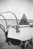 Barn i barnvagn iförd hemsydd åkpåse inv.nr 327956. 1940-talets andra hälft.