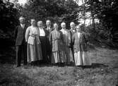 Män och kvinnor står i en skogsbacke. Längst till höger fotograf Gustav Anderssons föräldrar Ottilia och Johan August Andersson.