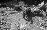 Ett stenbrott, Nubbstensberget i Mariebo utanför Jönköping. Järnvägsvagnar dragna av hästar forslar bort stenen.