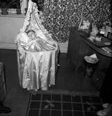 Bäck. Ett litet barn iförd dopklänning ligger i en babykorg med sänghimmel i en lägenhet i Jönköping.