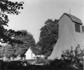 Kyrka, klockstapel och del av kyrkogård. Holms kyrka