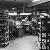Män arbetar vid olika maskiner för skotillverkning. En stor del av produktionen består av träskor med namnet Dalbo.    Holm. Se hembygden 1972, s. 156