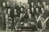 Musikkåren Exelsior. Kullings-Skövde Pojkar och unga män poserar med blåsinstrument och en stor trumma längst fram i mitten.