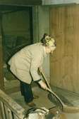 En äldre kvinna sopar golvet med en kvast. Före renovering?  Stegerhult  Liared