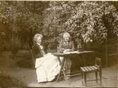Två damer i trädgård (Josephine och Lilly Breggren)